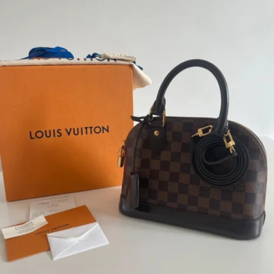 Louis Vuitton Alma BB damier ébène. SAC DE LUXE DE SECONDE MAIN AUTHENTIQUE CERTIFICAT D'AUTHENTICITE ENTRUPY. SAC DE LUXE D'OCCASION PAS CHER. PETITE MAROQUINERIE LV